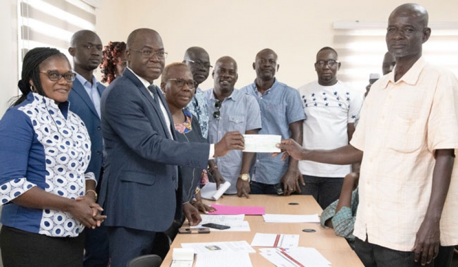 Le coordonnateur Ouattara Issa (à gauche) remettant le chèque à un impacté.