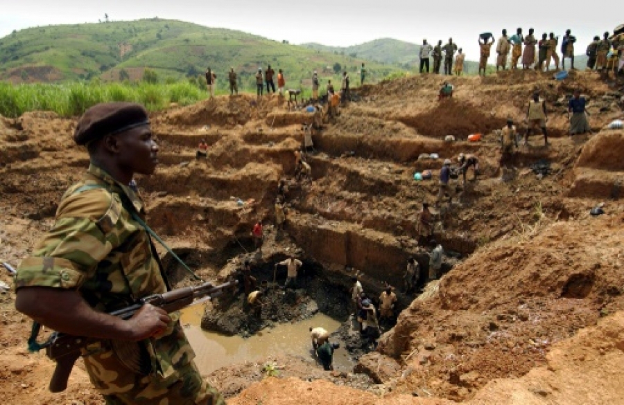 Un milicien surveille les ouvriers d'une mine d'or à ciel ouvert en Ituri, dans le nord-est de la RD Congo, le 18 juin 2003 | AFP/Archives | ERIC FEFERBERG