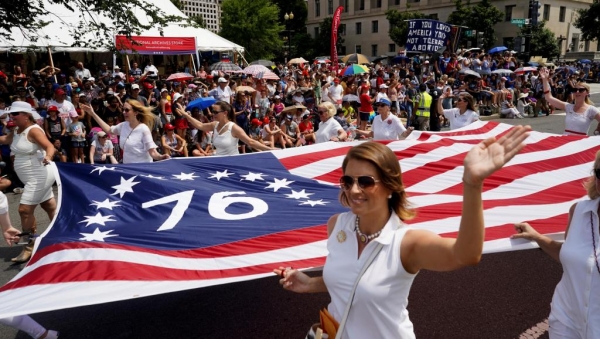 Les participants à la parade portent un drapeau américain lors de la commémoration de l’Indépendance à Washington, le 4 juillet 2019.