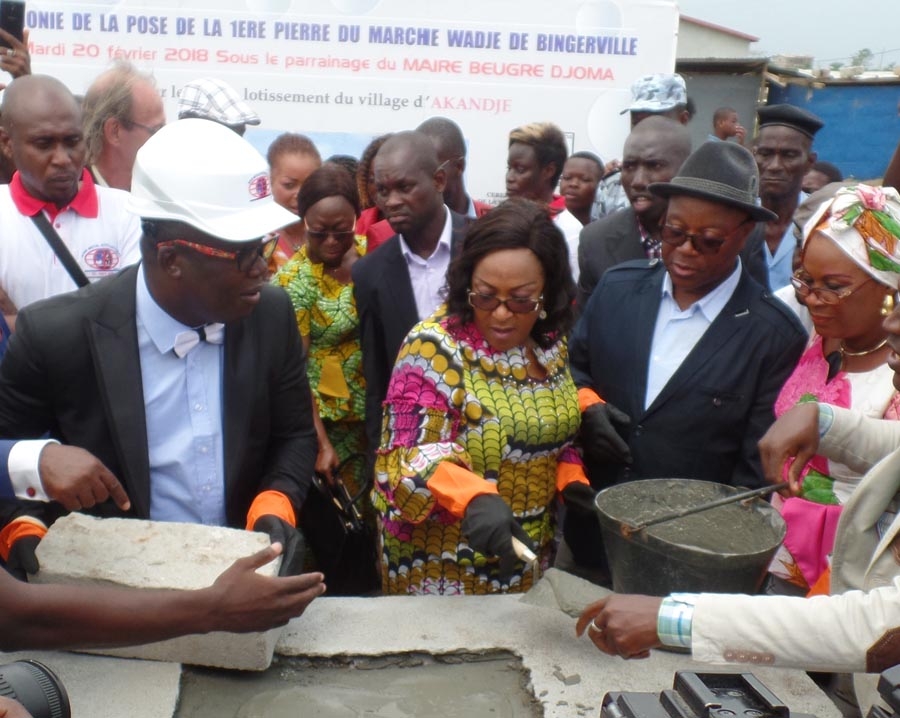Pose de la première pierre par Mme Touré Aya Virginie, sous les regards du maire Beugré Djoman et de Mme Vanié (à droite)