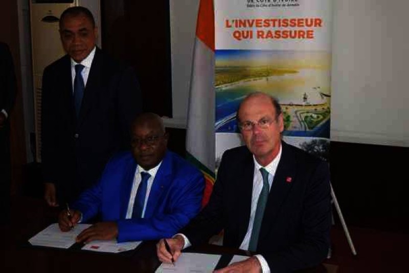 Le Directeur général de la CDC-CI, Lassina Fofana signant la convention avec la CDC France représentée par son DG, Eric Lombard, sous le regard attentif du ministre ivoirien de l'Economie et des Finances, Adama Coulibaly.
