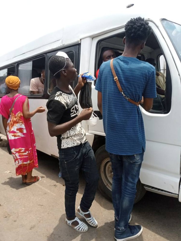 Un vendeur proposant des cache-nez à l'embarquement, dans une gare à Abidjan.