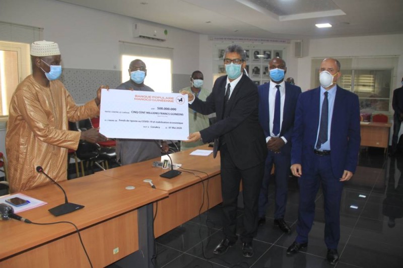Mamadi Camara, ministre guinéen de l’Economie et des Finances (à gauche) réceptionnant le chèque de 500 millions de francs guinéens des mains d'Abdeltif Jakani, directeur Pôle gestion des risques et directeur général par intérim de Bpmg. (Sercom BACI)