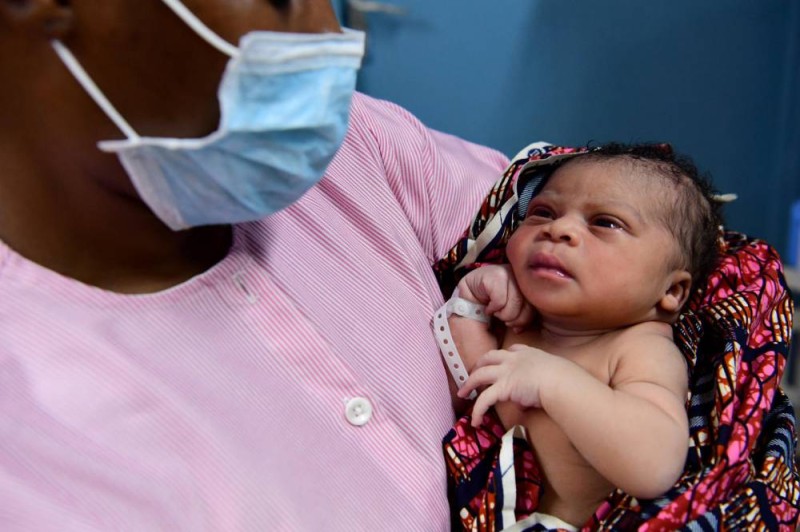 Une infirmière donne les premiers soins, avec un masque buccal, à un nouveau-né au centre de santé de Port Bouet, à Abidjan (DR)