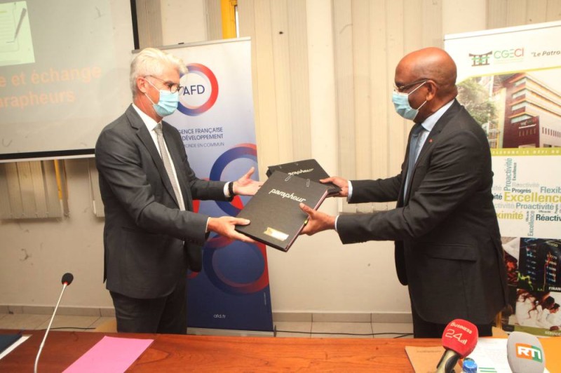 Echange des parapheurs entre le président de la Cgeci, Jean-Marie Ackah (à droite) et le directeur de l'Agence française de développement, Emmanuel Debroise. (Dr)