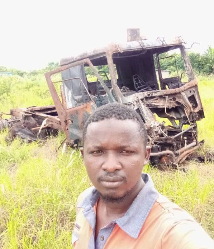 Le jeune opérateur économique posant devant la carcasse de son camion incendié