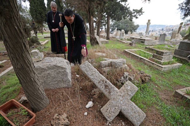 Hosam Naoum, archbishop and caretaker of the Protestant cemetery, inspects vandalised graves on Mount Zion outside Jerusalem's Old City on January 4, 2023. - Church authorities said the damage was discovered in the morning, while security camera footage from January 1 showed two men or boys vandalising the site while wearing Jewish attire. (Photo by AHMAD GHARABLI / AFP)