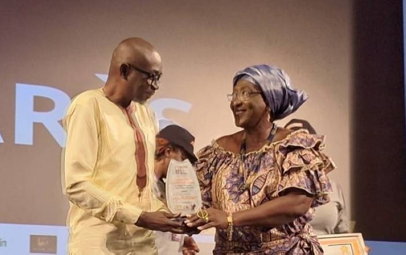 Serges N'guessant recevant son prix des mains de Mme Lysson Diomandé, directrice générale de l'Office national du cinéma de Côte d'Ivoire (Onac Ci)
