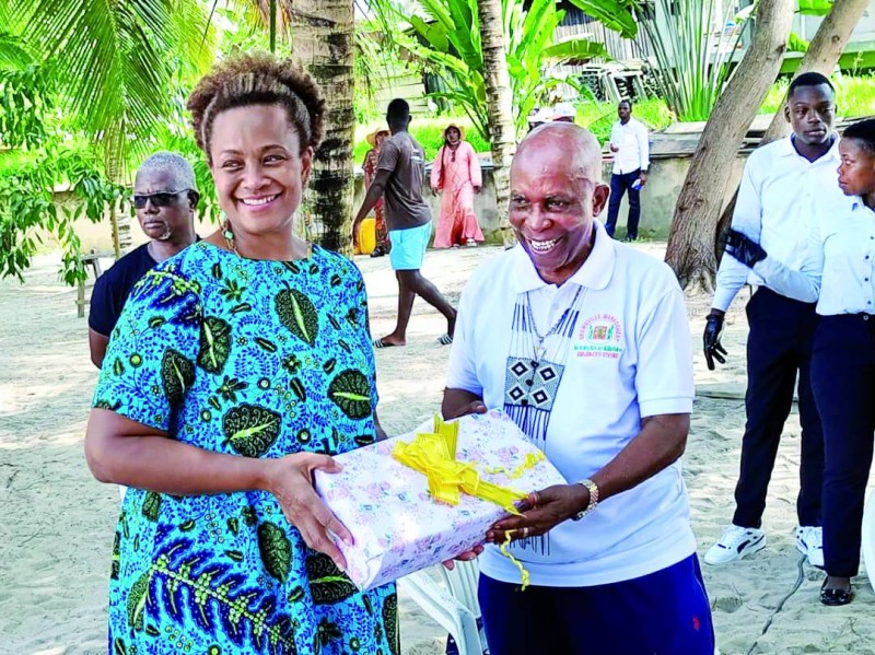 M. Brown, offrant un présent à l'ambassadrice des Etats-Unies en Côte d'Ivoire . Il veut faire en sorte que la journée afro-américaine soit perpétuée. Dr