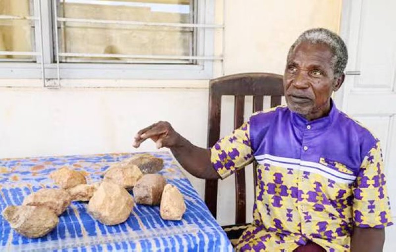 L’archéologue ivoirien François Guédé Yiodé présente des pierres utilisées par Homo sapiens il y a 150 000 ans, chez lui, à Abidjan, le 13 mars 2025. ISSOUF SANOGO/AFP.