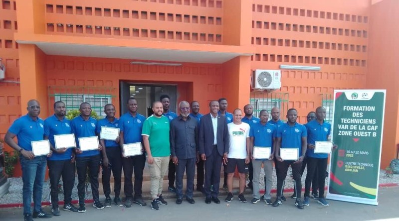 Les 14 techniciens VAR certifiés posant fièrement avec leurs parchemins aux côtés des officiels lors de la cérémonie de clôture au Centre technique national de football de Bingerville