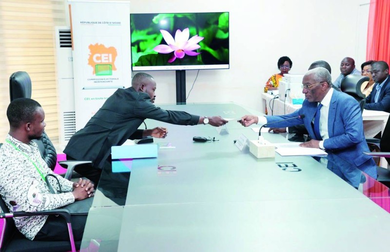 Dabé Yves Michel Junior en train de remettre son dossier au premier secrétaire permanent adjoint de la Cei, Emile Ebrottié.