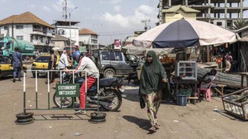  Une piétonne passant devant un marché dans le quartier de Cosa à Conakry, le 26 décembre 2025. (Image d'illustration) AFP - PATRICK MEINHARDT 