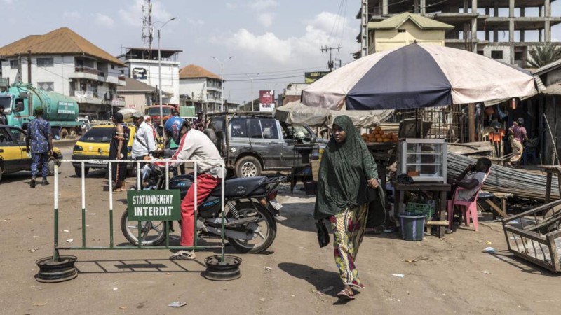 Une piétonne passant devant un marché dans le quartier de Cosa à Conakry, le 26 décembre 2025. AFP - PATRICK MEINHARDT
