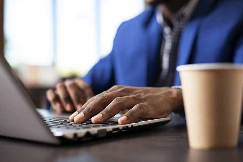 black-person-typing-laptop-desk