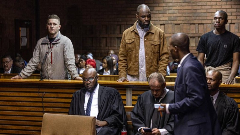 Stellio Gilles Robert Capo Chichi, alias Kemi Seba (au centre), son fils Khonsou Seba Capo Chichi (à droite), ainsi que leur complice présumé, François Van Der Merwe (à gauche), comparaissent devant le tribunal de première instance de Pretoria le 20 avril 2026. AFP - EMMANUEL CROSET