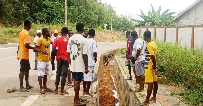 Des jeunes en train de curer les caniveaux.
